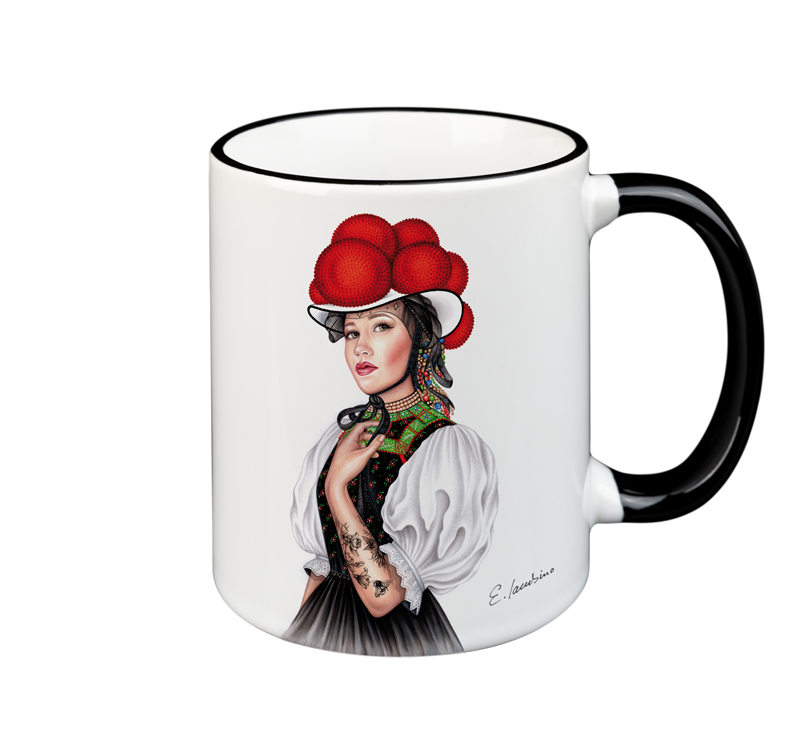 A white ceramic mug, both microwave safe and dishwasher safe, features an artistic illustration of a woman wearing a traditional outfit and a hat with large red pom-poms. The woman has a tattooed arm and is holding a black cat. The handle and rim of the mug are black. This is the MUG – Bollenhut Black Forest Bonnie by Cuckoo's Nest.
